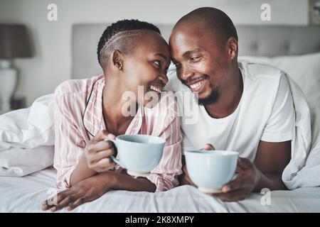 Kaffee und Sie, das ist alles, was ich brauche. Ein glückliches junges Paar genießen Kaffee zusammen im Schlafzimmer zu Hause. Stockfoto