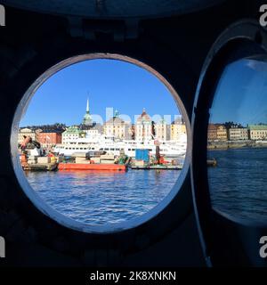 Eine vertikale Aufnahme einer Stadt in Schweden durch ein rundes Fenster eines Schiffes an einem sonnigen Tag Stockfoto