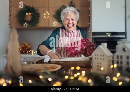 Glückliche ältere Frau beim Backen eines Weihnachtsgebäck. Stockfoto