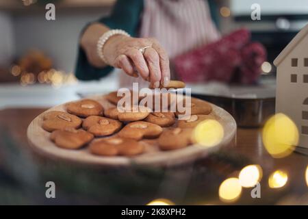 Nahaufnahme einer älteren Frau, die weihnachtliche Lebkuchen backt. Stockfoto