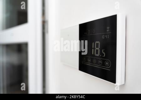 Klimaanlagenschirm an der Wand, der eine Lufttemperatur von 18 Grad Celsius anzeigt. Ein Gerät zur Steuerung der Fußbodenheizung. Stockfoto