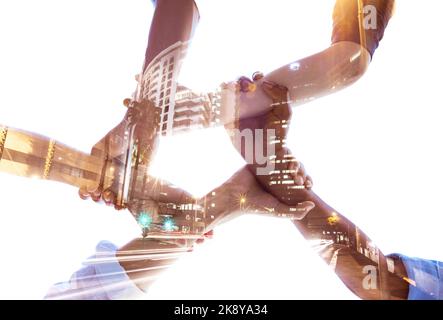Die Hände in den Händen halten, Teamarbeit und Vielfalt mit dem Aufbau einer doppelten Präsenz für globale Zusammenarbeit, Architekturwachstum und Erfolg in der Gemeinschaft. Niedriger Winkel Stockfoto