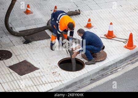 Galicien, Spanien; 30. september 2022: Zwei Arbeiter auf der Straße der Stadt, die die Blockierung eines Kanals mit einer Rohrleitung aufheben Stockfoto