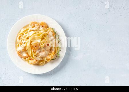 Pasta mit Meeresfrüchten. Pappardelle mit Garnelen und Sahnesauce auf einem weißen Teller, mit frischem Thymian, von oben mit einem Platz für Text geschossen Stockfoto