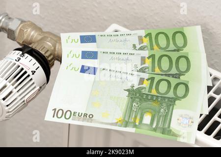 300 Euro liegen auf dem Heizkörper. Drei Papierbanknoten zu je 100 Euro. Ein Symbol für steigende Heizkosten. Geld, um die Rechnungen zu bezahlen. Stockfoto