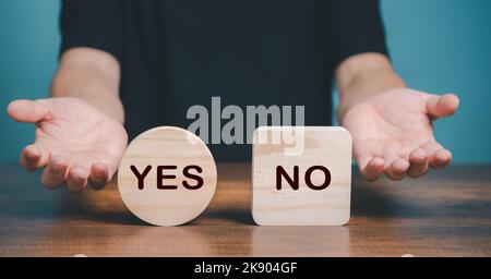 Ja oder Nein Auswahlsymbol. Hand macht eine Frage Geste zur Wahl zwischen zwei Würfel mit Ja und Nein-Symbol auf dem Schreibtisch. Business und Ja oder Nein Wahl CO Stockfoto