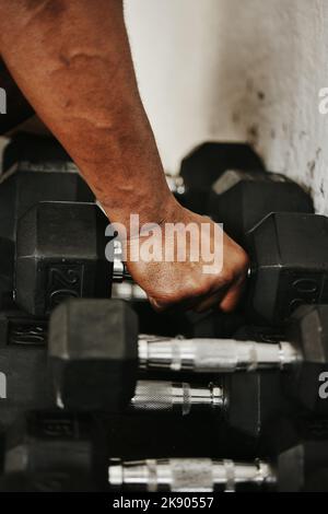Hand, Hantel und Fitness mit einem Mann Bodybuilder in einem Fitnessstudio für Bewegung, Training oder ein Training mit Gewichten. Stockfoto