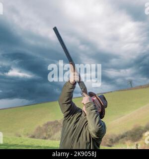 Mann, der Fasane mit dramatischem Himmel schießt Stockfoto