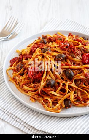 Hausgemachte Thunfisch-Linguine-Pasta mit Tomaten, Oliven und Kapern auf einem Teller, Seitenansicht. Stockfoto