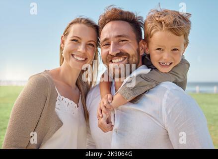 Park, Portrait und glückliche Familie lieben es, in der Natur im Freien zu sein, um Sommerferien, Urlaub oder Wochenende zu genießen. Aufgeregt Kind umarmt oder Schweinchen Rücken an Stockfoto