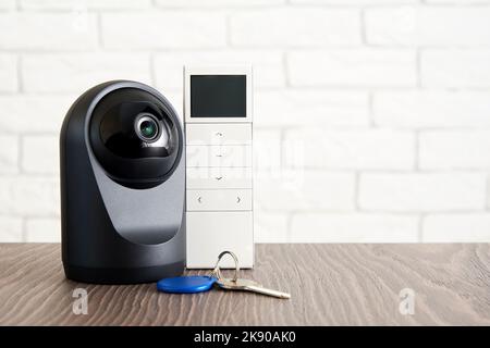 Sicherheits-IP-Kamera, Schlüssel und Fernbedienung für den Hauszugang. Smart-Home-Geräte und Datenschutz Stockfoto