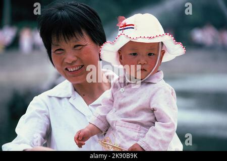 China. Xian. Nahaufnahme des Porträts einer chinesischen Frau, die ein Kind hält. Stockfoto