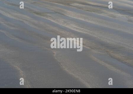 Schwarzer vulkanischer Sandstrand mit Wellenmustern Stockfoto