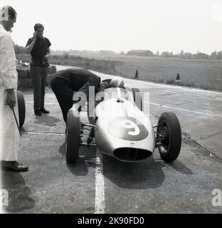 1962, ein historischer Mann, der in einem einsitzigen Rennwagen neben einer Rennstrecke mit Mechaniker in Geoff Clarkes Motor Racing Stables sitzt, einer Fahrschule im Finmere Aerodome, einem stillstehenden RAF-Flugplatz in der Nähe von Buckingham, England, Großbritannien. Die 1.000-ccm-Einsitzer der Rennschule waren Formel-Junior-Coopers mit Heckmotor. Stockfoto