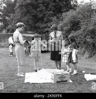 1964, historisch, juli und kleine Kinder draußen auf einem Fete spielen eine Partie fangen einen Fisch, mit Stöcken mit Magnetik befestigt, England, Großbritannien. Stockfoto