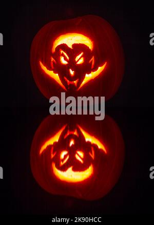 Kürbis geschnitzt mit dracula Gesichtsdesign beleuchtet im Dunkeln mit zusätzlicher Reflexion - geschnitzter Kürbis - Jack O Laterne für Halloween Stockfoto