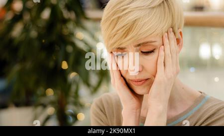 Portrait kaukasischer Erwachsener mittleren Alters 40s Frau müde Dame erschöpft gestresst Frau hält Kopf von Bad Problem Kopfschmerzen schmerzhafte Migräne leiden Stockfoto