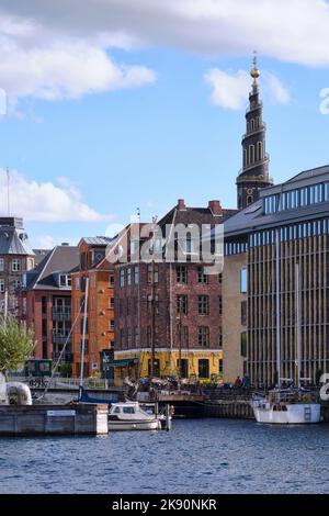 Kopenhagen, Dänemark - 2022. September: Blick über den Kanal in der Stadt gesäumt von historischen Gebäuden im Viertel Christianshavn und der Spitze der Kirche Stockfoto