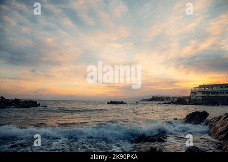 Eine wunderschöne Aussicht auf ein welliges Meer, das den Betonpier spült Stockfoto