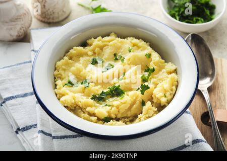 Kartoffelpüree. Heiße Kartoffelpüree mit Butter, frischen Petersilienkräutern und Pfeffer in einer Schüssel auf Schiefer-, Stein- oder Betonböden. Köstliche cremige Mas Stockfoto