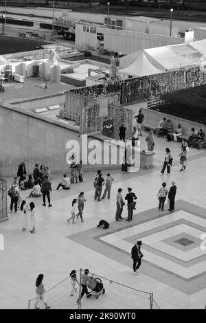 Eine vertikale Graustufe des Trocadero-Platzes voller Menschen, die in Paris, Frankreich, spazieren und sitzen Stockfoto