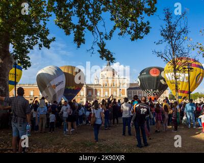 Das Publikum konzentriert sich beim Aranjuez Hot Air Balloon Festival um die Ballons, während sie aufgeblasen werden. Stockfoto