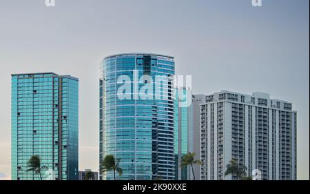 Skyline von Honolulu bei Sonnenuntergang mit Palmen vor dem Hotel Stockfoto