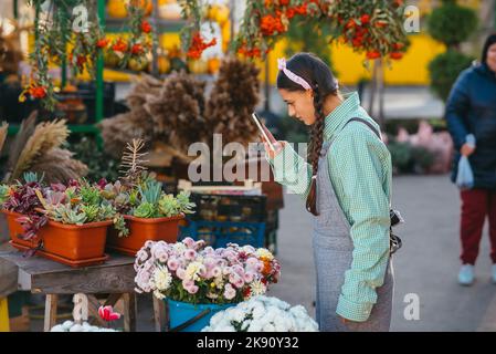 Junge Frau, die mit ihrem Smartphone eine Topfpflanze fotografiert Stockfoto