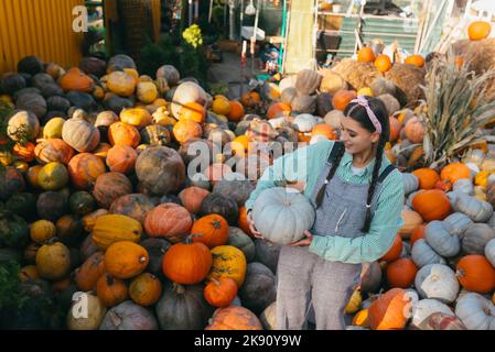 Bäuerin mit Kürbis auf dem Hintergrund der Herbsternte. Stockfoto