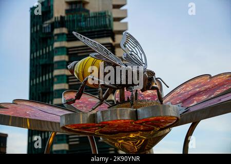 Nahaufnahme einer Bienenstatue mit dem Price Tower im Hintergrund in Bartlesville, Oklahoma Stockfoto