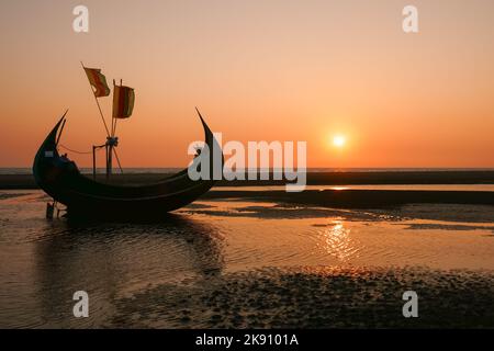 Malerische Sonnenuntergangslandschaft mit einem wunderschönen traditionellen hölzernen Fischerboot, bekannt als Mondboot am Strand, Cox's Bazar, Bangladesch Stockfoto