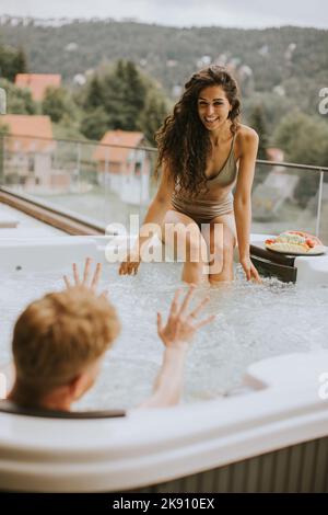 Attraktives junges Paar, das im Urlaub im Whirlpool im Freien ist Stockfoto