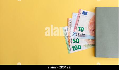 Verschiedene Euro-Banknoten neben einem Notizblock auf gelbem Hintergrund, Kosten- und Budgetplanung. Bargeld in Papierwährung, Zahlung, Einnahmen und Einsparungen, Th Stockfoto