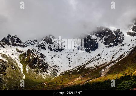 Die wunderschönen schneebedeckten Berge im Yumesamdong Tal mit flauschigen Wolken überzogen Stockfoto