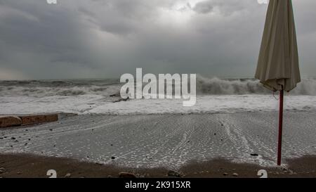 Stürmisches Wetter und eine Betonstruktur Küstenbarriere mit dem Ozean dahinter und Inseln im Hintergrund. Stockfoto