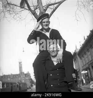 1940s Seeleute auf Landgang. Zwei dänische Seeleute sehen glücklich und verspielt aus, während einer auf den Schultern seiner Freunde sitzt und grüßelt. Dänemark Kopenhagen 1946 Ref. T51-1 Stockfoto