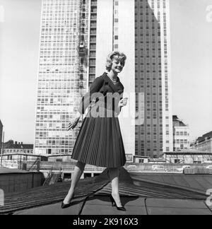 In der 1950s. Eine Frau, die ein Outfit aus dem Jahr 1950s mit Jacke und Rock in passender Dunkelheit modelliert. Im Hintergrund der neu fertiggestellte Wolkenkratzer, in dem die schwedischen Finanzämter untergebracht sind. Schweden 1959 Kristoffersson Ref. CH21 Stockfoto