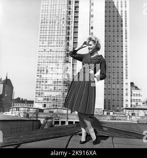 In der 1950s. Eine Frau, die ein Outfit aus dem Jahr 1950s mit Jacke und Rock in passender Dunkelheit modelliert. Im Hintergrund der neu fertiggestellte Wolkenkratzer, in dem die schwedischen Finanzämter untergebracht sind. Schweden 1959 Kristoffersson Ref. CH21 Stockfoto