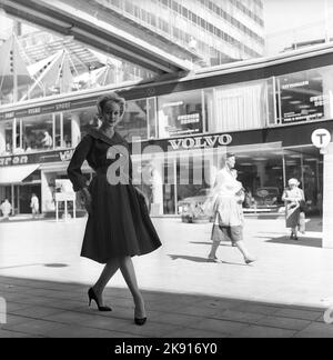 In der 1950s. Eine Frau, die ein Outfit aus dem Jahr 1950s mit Jacke und Rock in passender Dunkelheit modelliert. Im Hintergrund eine Straße im Zentrum von Stockholm und ein Volvo-Geschäft, in dem die Modelle Amazon und PV ausgestellt sind. Schweden 1959 Kristoffersson Ref. CH21-9 Stockfoto