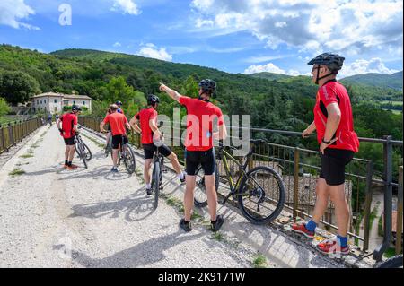 Eine Gruppe norwegischer Radfahrer mittleren Alters mietete Fahrräder, die sich auf der Caprareccia-Brücke auf der stillstehenden Eisenbahn Spoleto nach Norcia ausruhten. Umbrien, Italien. Stockfoto