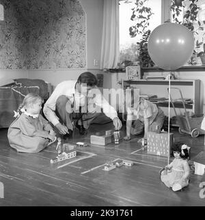 In der 1950s. Ein Mann mit zwei Kindern spielt auf dem Boden mit Autos und Häusern, macht Straßen und erzieht die Kinder vielleicht im Straßenverkehr. Das Jahr ist 1958. Schweden Ref. CV79 Stockfoto