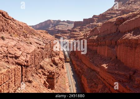 Ein Zug, der eine Ladung Kali aus einer Mine in der Nähe von Moab, Utah, schleppt, macht einen steilen Anstieg durch einen tiefen künstlichen Straßenschnitt. Der Schnitt ist mehr als Stockfoto