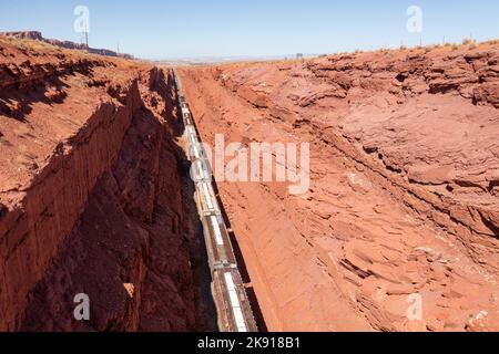 Ein Zug, der eine Ladung Kali aus einer Mine in der Nähe von Moab, Utah, schleppt, macht einen steilen Anstieg durch einen tiefen künstlichen Straßenschnitt. Der Schnitt ist mehr als Stockfoto