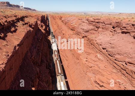 Ein Zug, der eine Ladung Kali aus einer Mine in der Nähe von Moab, Utah, schleppt, macht einen steilen Anstieg durch einen tiefen künstlichen Straßenschnitt. Der Schnitt ist mehr als Stockfoto