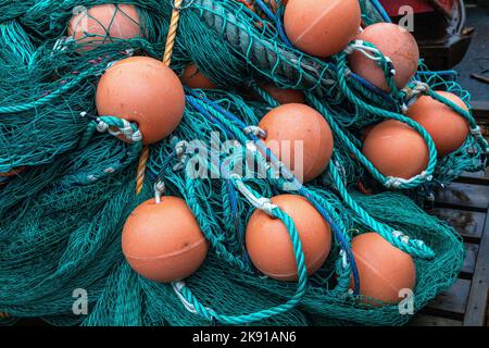 Haufen von orangefarbenen Fischerbojen und Fischernetzen, an einem Kai im Hafen von Bergen, Norwegen Stockfoto