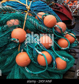 Haufen von orangefarbenen Fischerbojen und Fischernetzen, an einem Kai im Hafen von Bergen, Norwegen Stockfoto