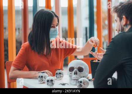 Die Frau und der Mann in Masken reden über Schädel und Fledermaus halloween Spielzeugkollektion Stockfoto