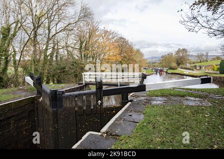 Familie auf dem Schmalboot „Silsden Boats“, das Schleusen ausfährt, während sie in Richtung Gargrave und dem entfernten Sharp Haw & Rough Haw fährt 25.. Oktober 2022. Stockfoto