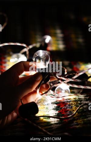Weihnachtslicht in Kinderhand. Elektrisches Weihnachtslicht im dunklen Raum. Stockfoto