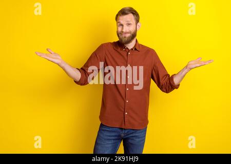 Foto von positiven lustigen Mann gekleidet trendige Kleidung zeigt Arm kann sagen, wo neue Friseurladen traurig isoliert auf gelbem Hintergrund Stockfoto